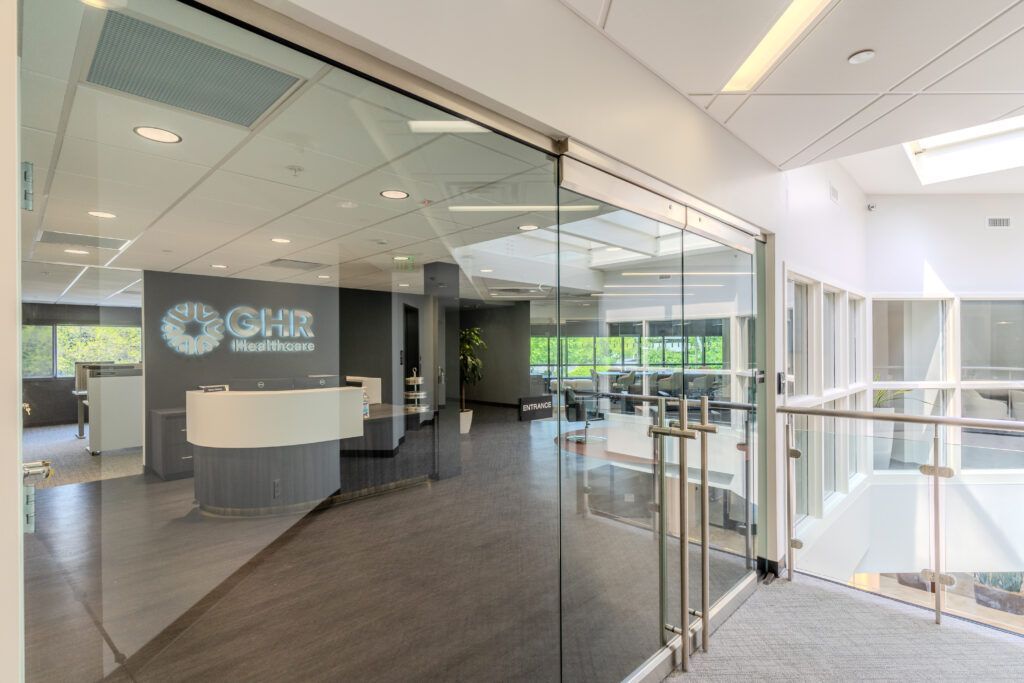 View of GHR Healthcare's front desk through glass doors with skylight above